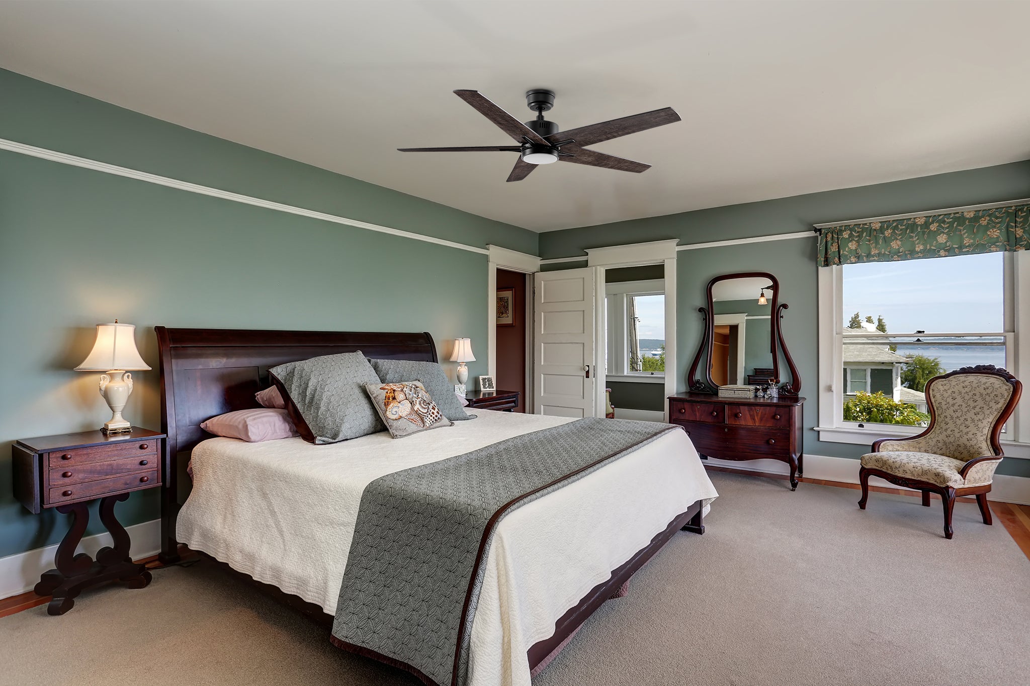 A large 52-inch ceiling fan with an LED light mounted in a spacious traditional-style bedroom with a green accent wall, neutral furniture, and elegant decor. 