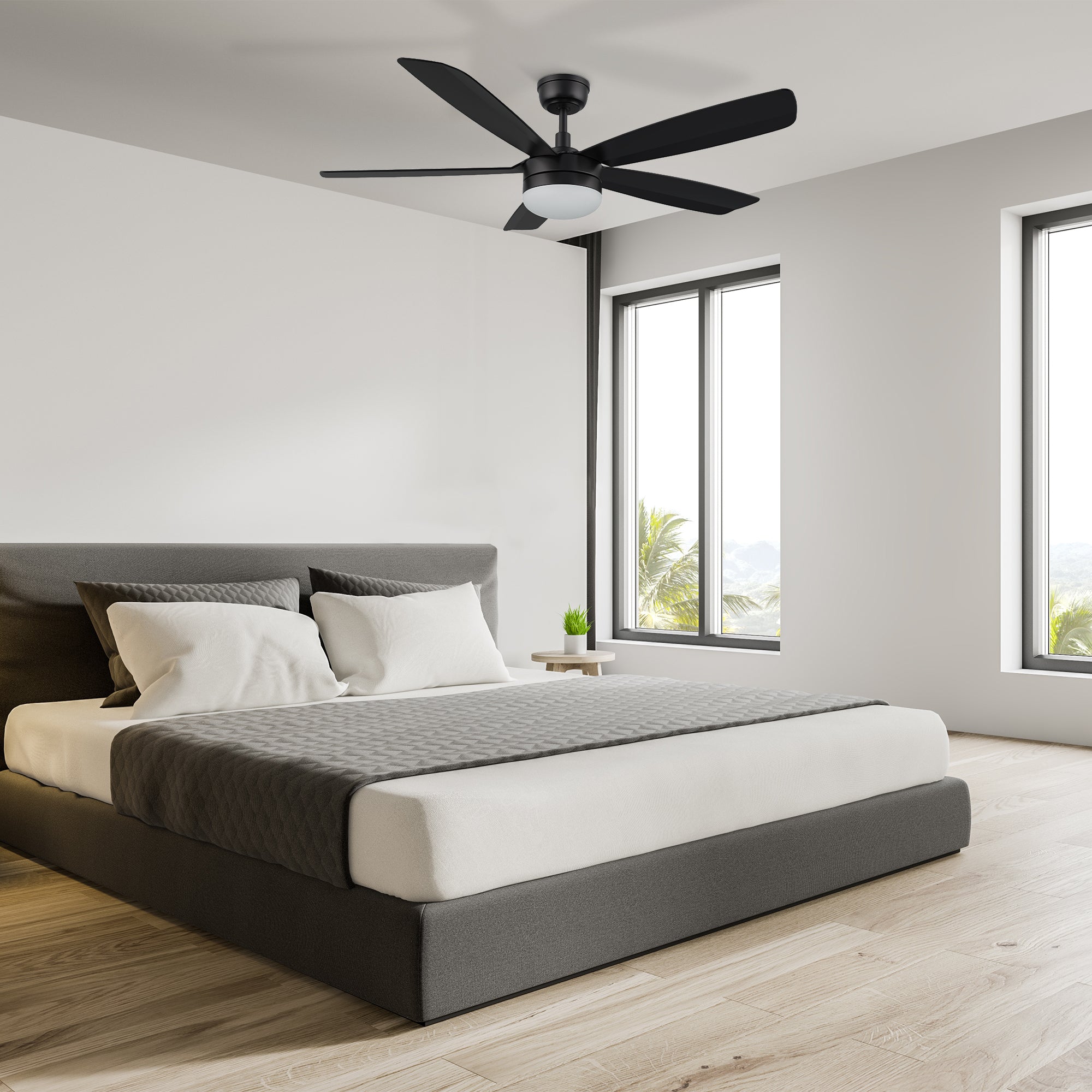 A stylish 52-inch black ceiling fan with a central light fixture installed in a modern bedroom with minimalist decor, featuring a low platform bed and large windows. 