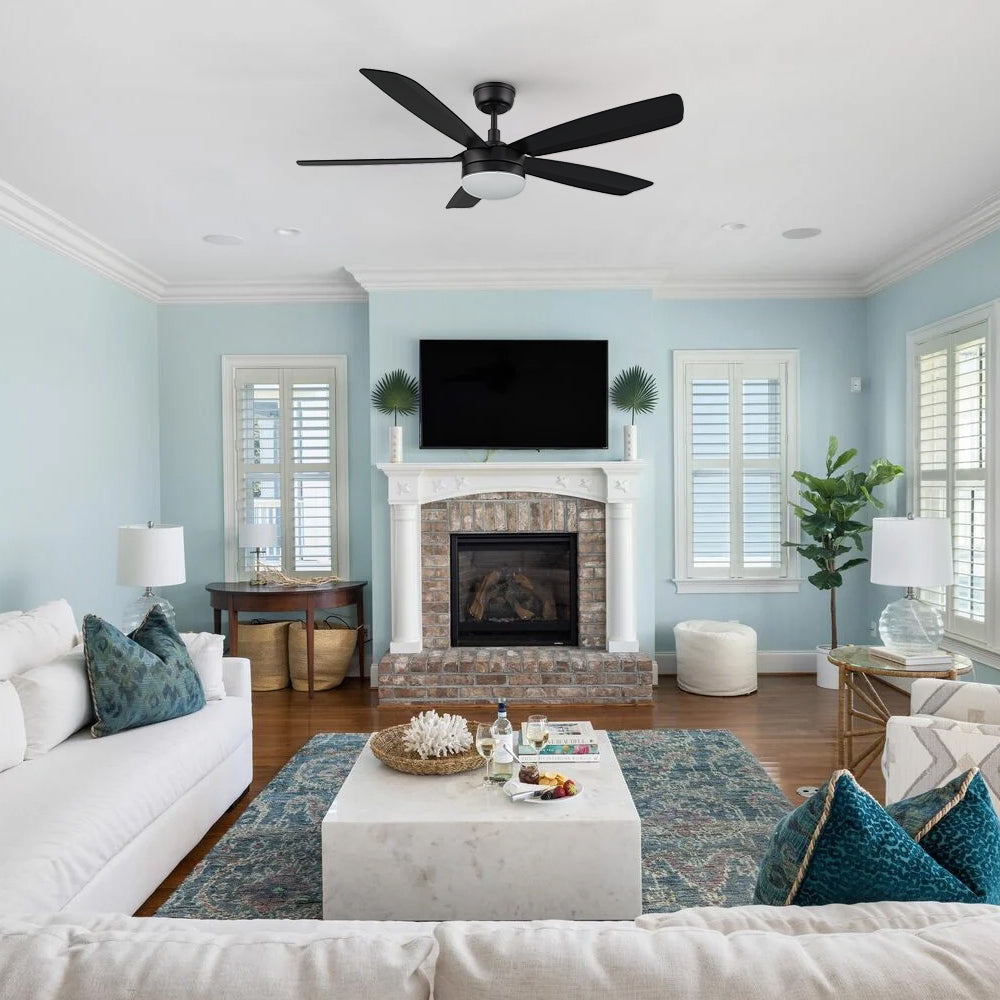 A 52-inch black ceiling fan with LED light, installed in a contemporary living room with modern furniture and large windows, from the Carro Smafan Rivers collection. 