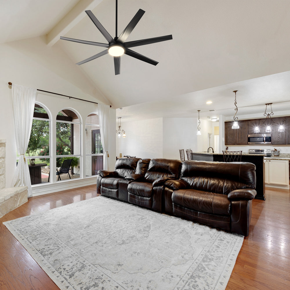 A spacious traditional living room featuring the Daventry 65-inch DC Motor Ceiling Fan with LED Light and Remote. The fan’s sleek black finish complements the warm décor, while its energy-efficient LED light kit and powerful airflow keep large indoor living spaces bright and comfortable. 