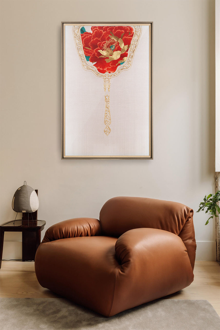 An Embroidery artwork of a royal fan embroidered with red peony flowers as the wall art and hung over the brown sofa.