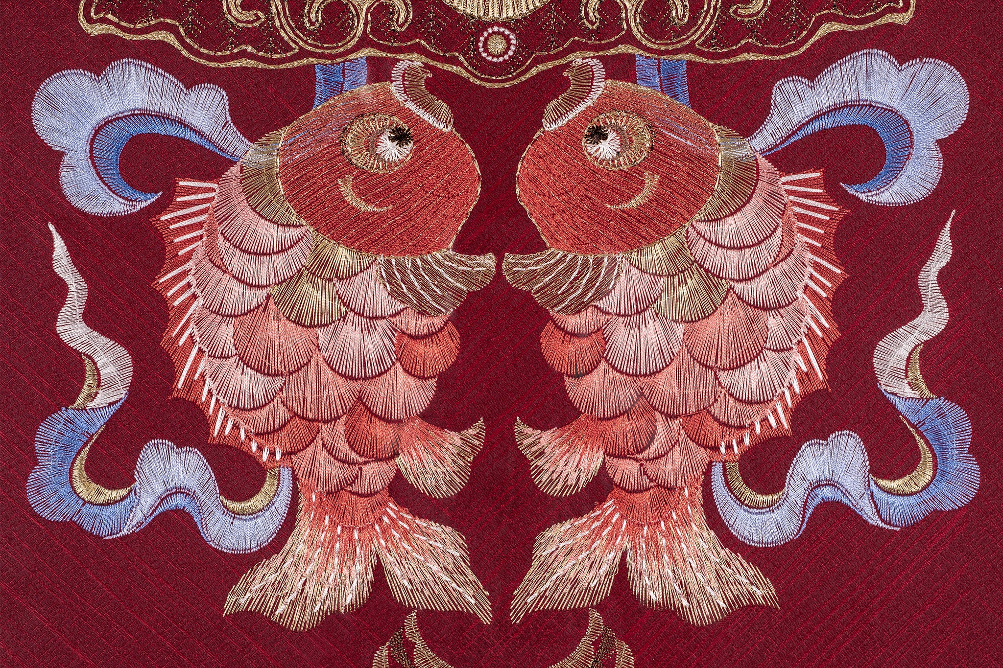 An embroidered work of art with a red background, embroidered with two koi carp.