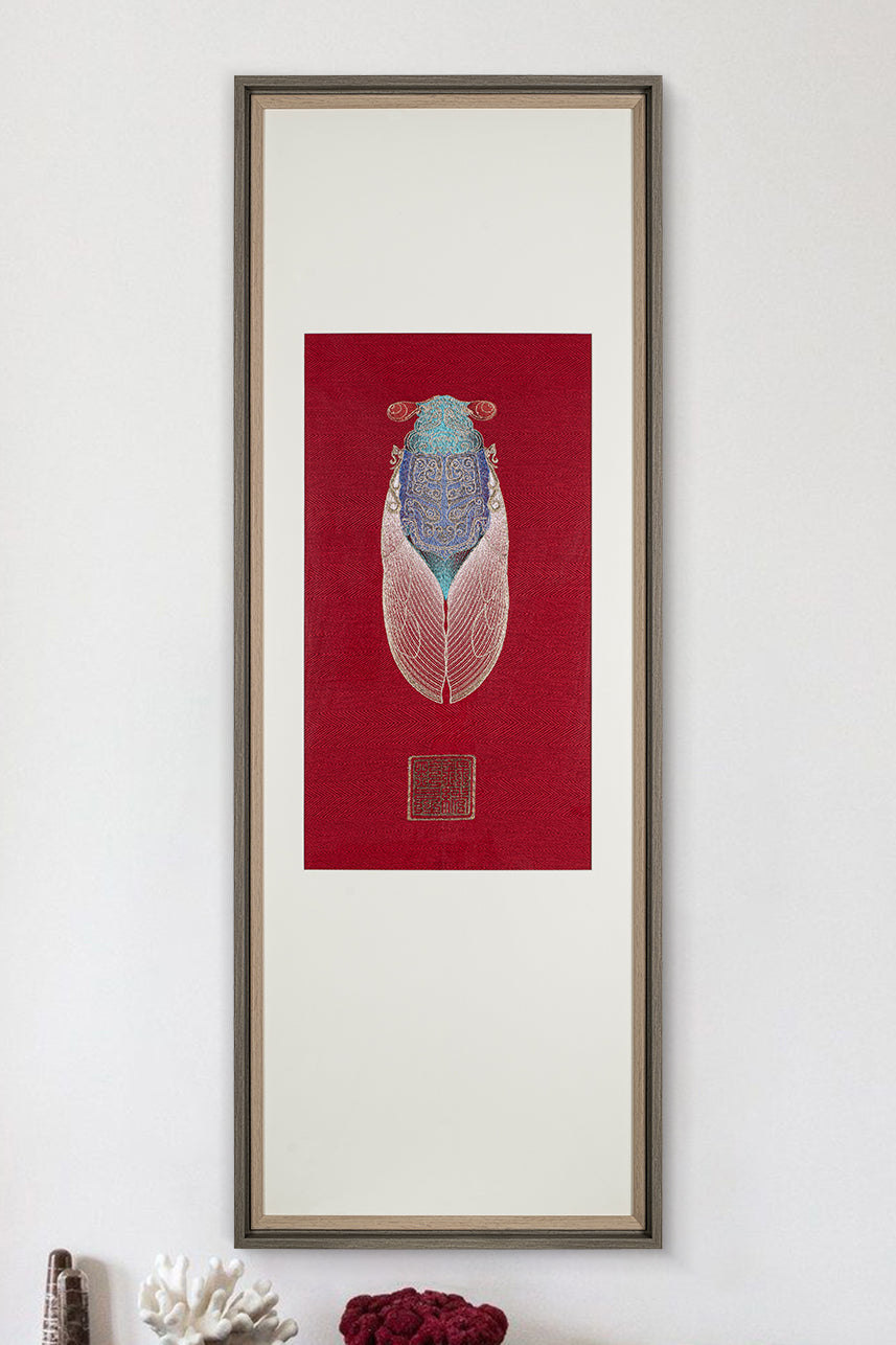 A framed embroidery artwork featuring a cicada design displayed on a white wall. The artwork has a red background and detailed embroidery in blue and white thread.