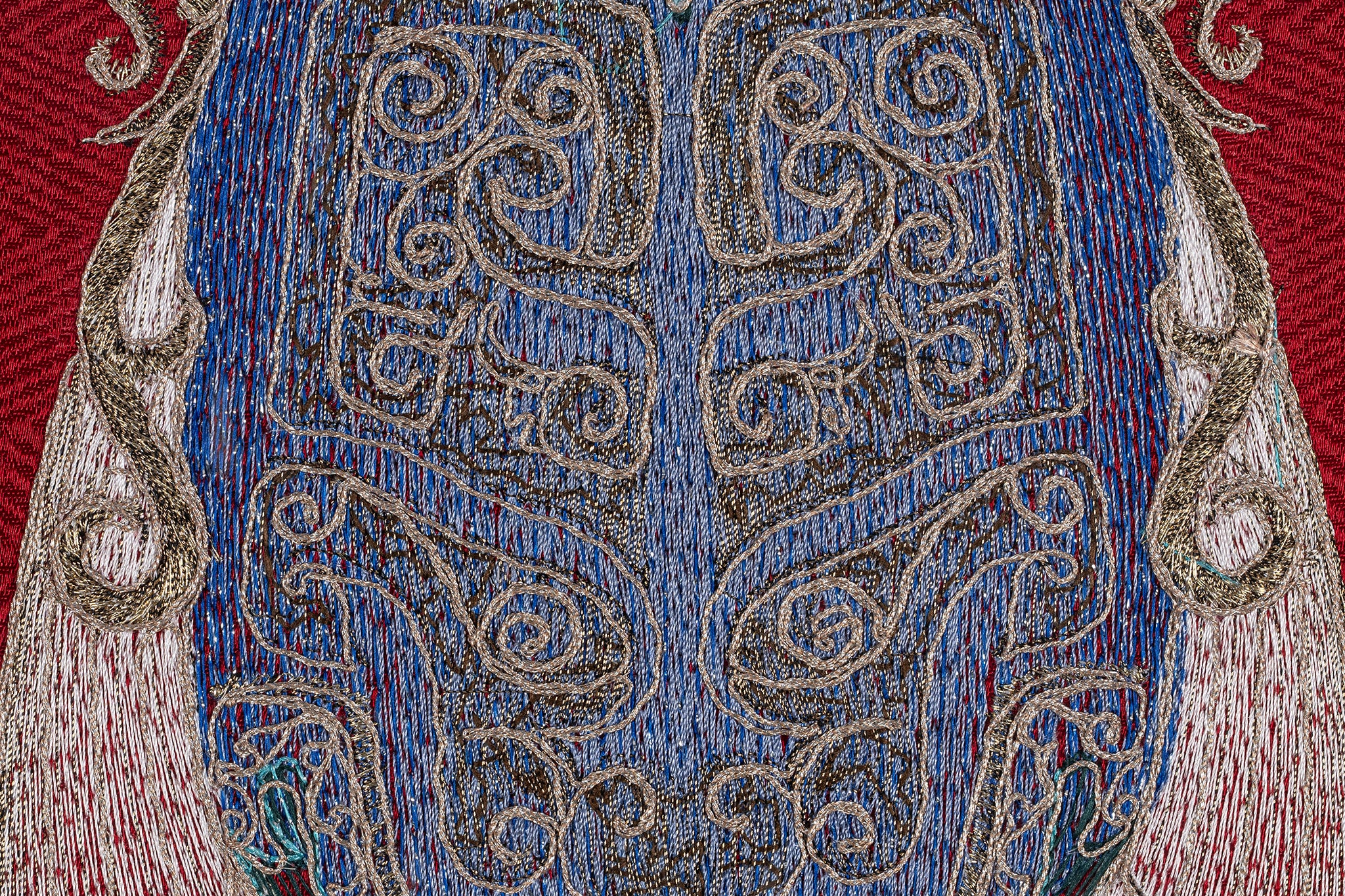 Close-up of the chest details of a framed embroidery artwork featuring a cicada design. The intricate embroidery showcases detailed patterns in blue and white thread on a red background.