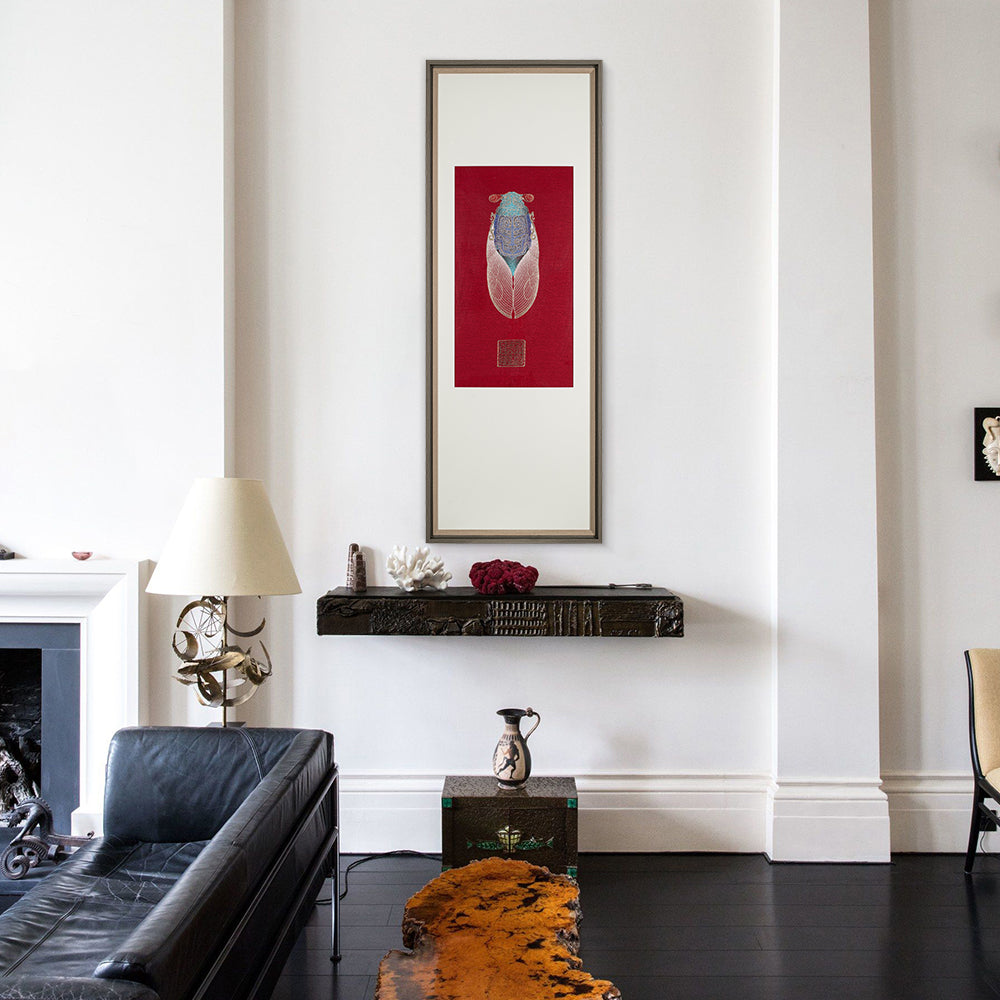 A living room with a side table and a fireplace. A framed embroidery artwork featuring a cicada design hangs above the side table, complementing the room's decor.