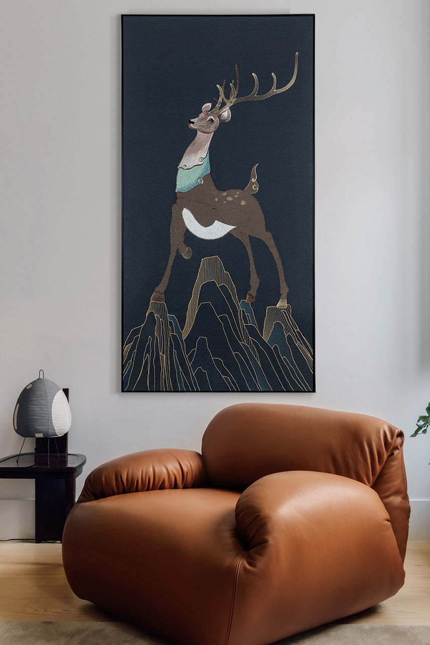 Framed embroidery fine wall art of a sika deer design displayed in a cozy living room with warm-toned furniture.