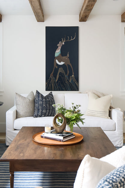 Framed embroidery fine wall art of a sika deer design displayed in a living room with a mix of contemporary and rustic elements.