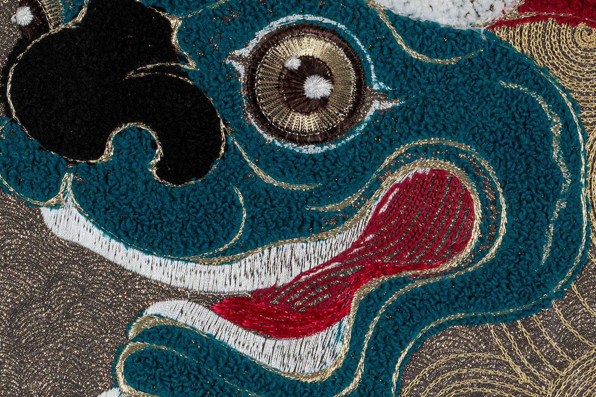 Close-up of framed embroidery artwork highlighting the lion design with detailed eye and fur elements.