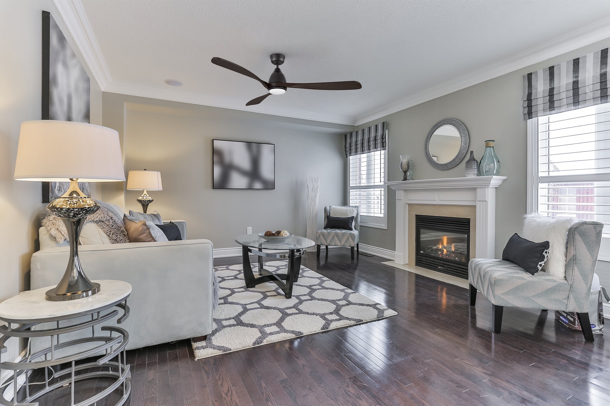 The Nephele black ceiling fan with an LED light is installed in a contemporary living room with minimalist decor, showcasing its large 60-inch blade span and smooth airflow performance.