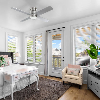 Traditional white-walled bedroom featuring a wooden desk, a plush armchair with a pink pillow, and a silver flush-mount ceiling fan in brushed nickel steel finish centered above a textured area rug. 