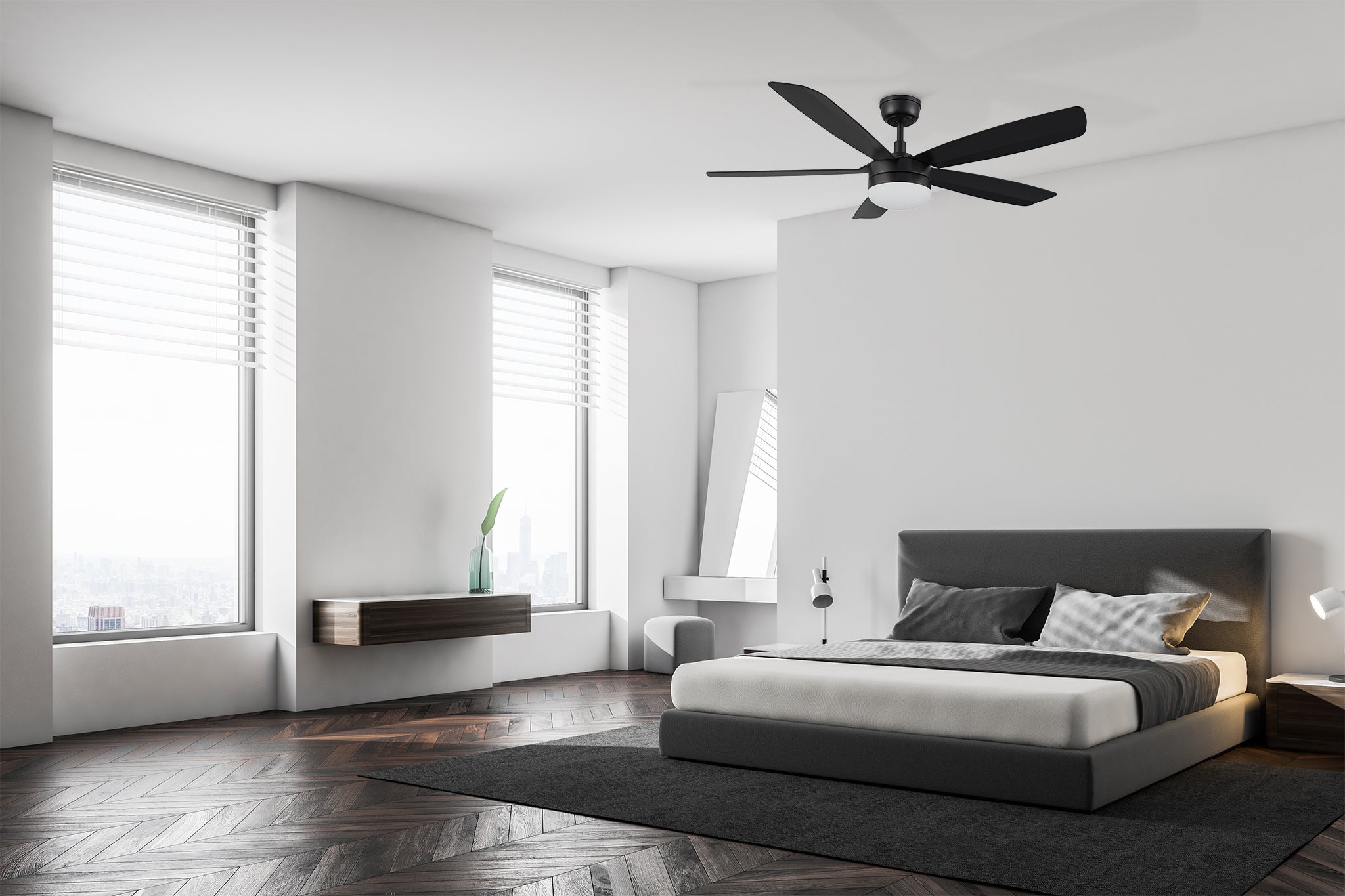 Modern bedroom with a minimalist design, featuring a black ceiling fan with integrated LED light, centered on the ceiling above a gray upholstered bed with white and gray bedding. The room is brightened by large windows with cityscape views and includes dark wood flooring and simple furniture.