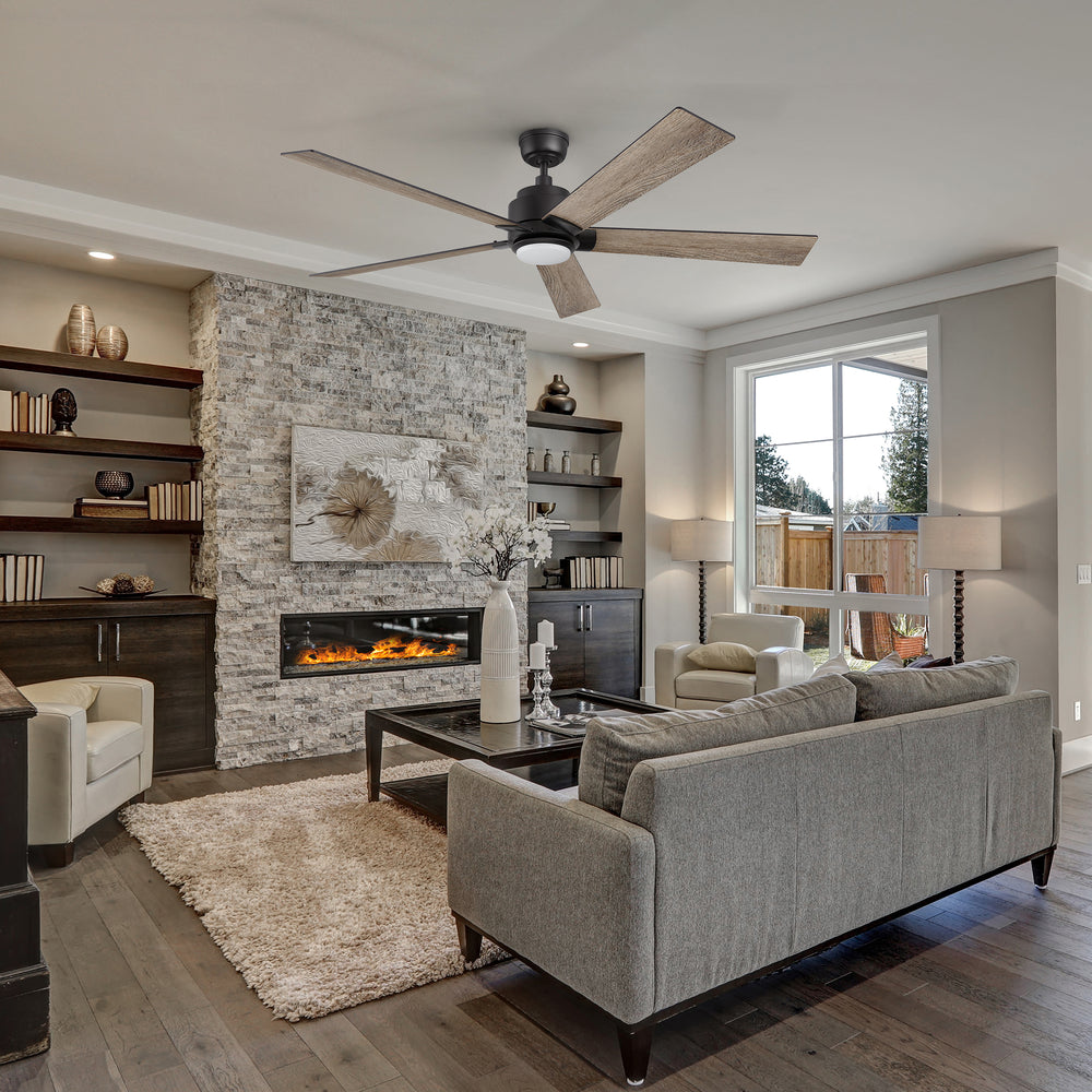 Modern living room featuring the Smafan Carro Aspen 60-inch ceiling fan with matte black hardware and wood-tone blades, elegantly complementing a gray stone fireplace, built-in shelves, and contemporary furniture in neutral tones. 