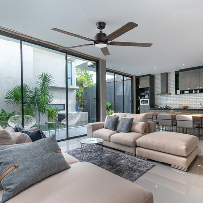 Modern living room featuring the Smafan Carro Essex 60-inch ceiling fan with matte black hardware and wood-tone blades, elegantly complementing a gray stone fireplace, built-in shelves, and contemporary furniture in neutral tones. 