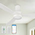 Close-up view of the white Coleman 52-inch smart flush mount ceiling fan mounted on a white living room ceiling. The modern low-profile fan features an integrated bright LED light and durable ABS blades. Remote control, smartphone app, and wall control shown in the lower left corner. 