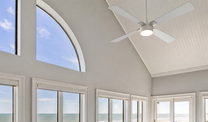 White Smafan Admiral 52-inch ceiling fan with light installed on a high vaulted ceiling in a coastal living room with large ocean-view windows. 