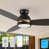 Black and gold flush mount smart ceiling fan with LED light installed on a patio ceiling, showing app, remote, and wall control options with an Energy Star logo. 
