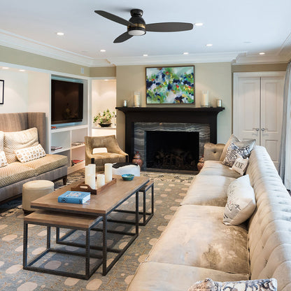Biscay Black and gold flush mount 3-blade ceiling fan with LED light installed on the ceiling of a modern luxury living room with a fireplace. 