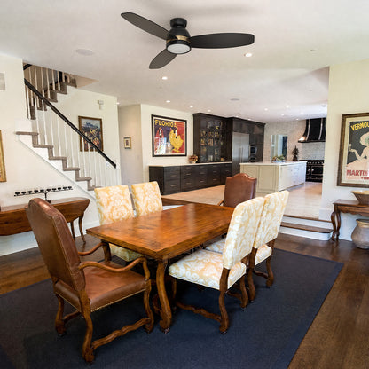 Black and gold flush mount 3-blade ceiling fan with LED light installed in a transitional style dining room and kitchen area. 