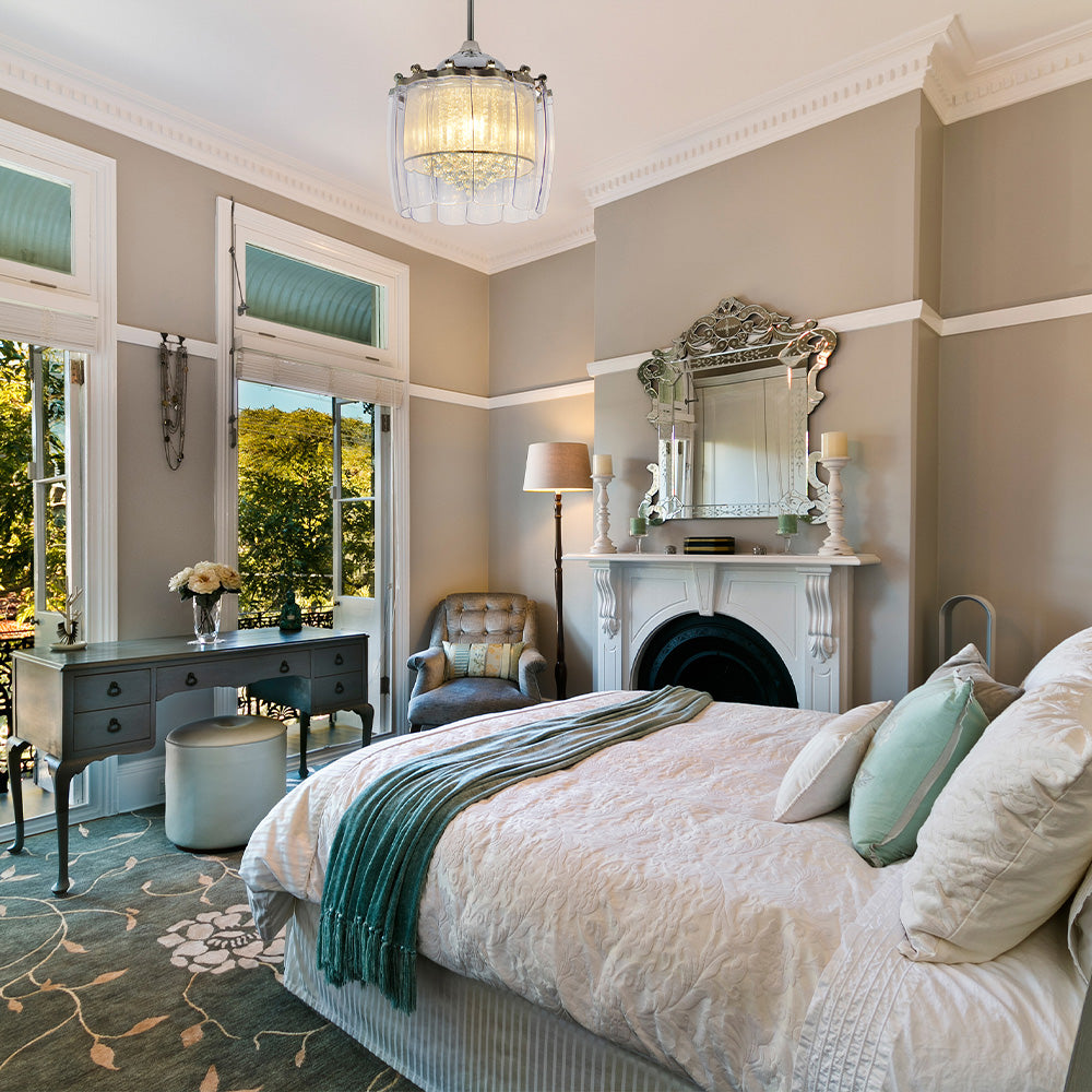 Retractable blade crystal fandelier ceiling fan with light accenting an elegant master suite featuring French patio doors and a plush green rug.