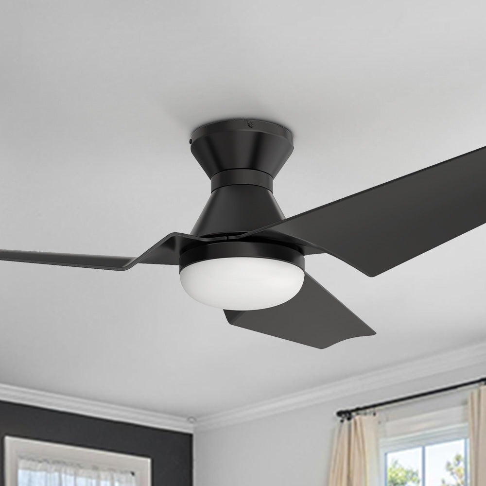 Close-up of a matte black, three-blade ceiling fan with integrated LED light, flush mounted on a white ceiling in a modern interior. 