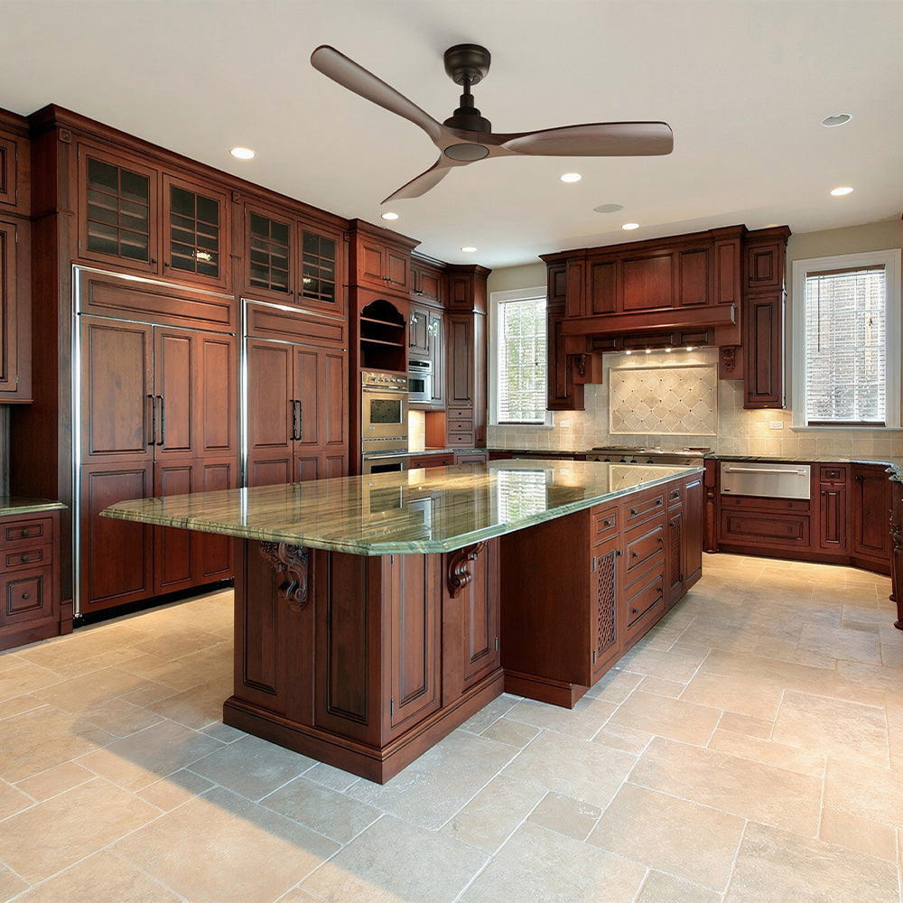 Large, luxurious kitchen with rich wood cabinetry, a green marble-topped island, light tile flooring, and a dark bronze three-blade ceiling fan. 
