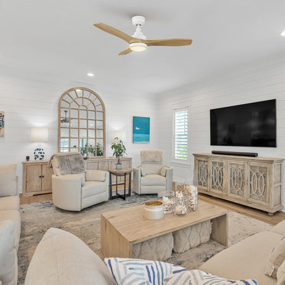 Rustic living room with wood tones, console cabinet, wall-mounted TV, and greenery; Ultiem 48-inch wood fan in white with LED light centered above the seating area for warm illumination. 