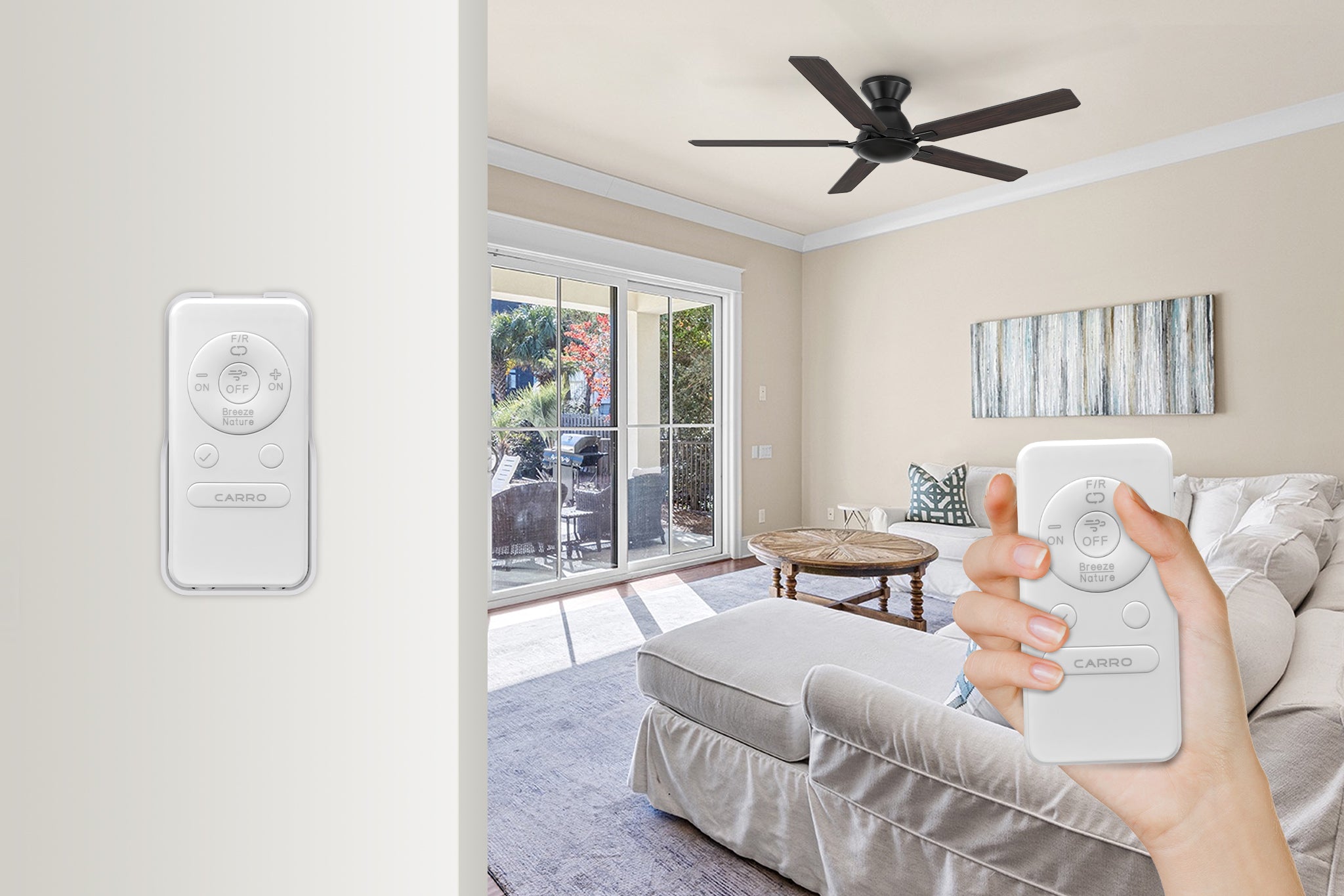 An interior view of a modern living room featuring light beige walls, hardwood flooring covered by a large area rug, and an off-white slipcovered sofa. A black five-blade Smafan Ventu 52-inch flush mount ceiling fan is mounted on the white ceiling. A glass sliding door opens to an outdoor patio area. In the foreground, a person's hand holds a white "CARRO" branded remote control, with an identical remote also shown mounted to a nearby wall.