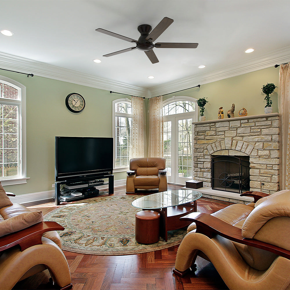 Black flush mount five-blade ceiling fan with wood blades and no light in a traditional living room with a stone fireplace and arched windows. 
