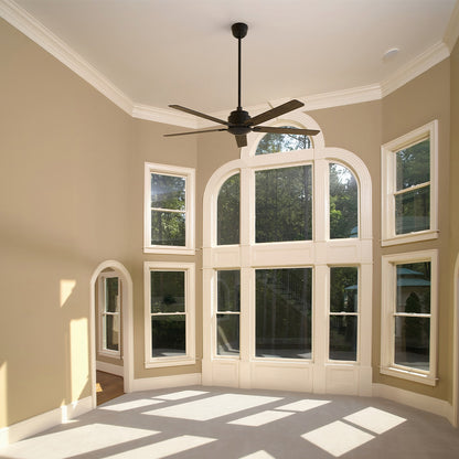 An interior view of a room with tall, arched bay windows, featuring a black ceiling fan mounted on a long downrod. The room has light tan walls and a light-colored carpet, with strong shadows cast across the floor by the abundant sunlight coming through the windows. The fan is consistent with a Smafan Warwick 60-inch model, which is typically a black ceiling fan without a light. 