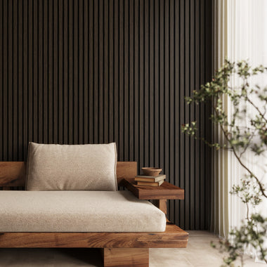 Smoked oak acoustic slat wood wall panels installed behind a sofa in a modern living room, creating a sophisticated backdrop.