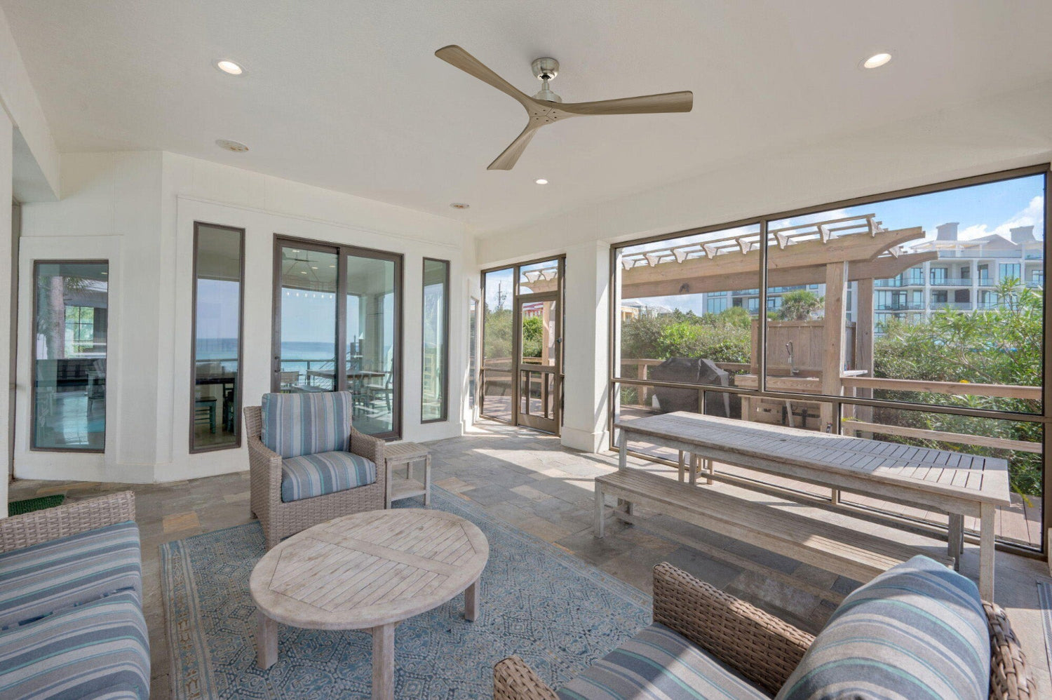 Thora 60 inch 3-blade wood ceiling fan without light installed on a modern screened-in patio with coastal wicker furniture, a rustic wooden dining table, and a blue patterned rug.