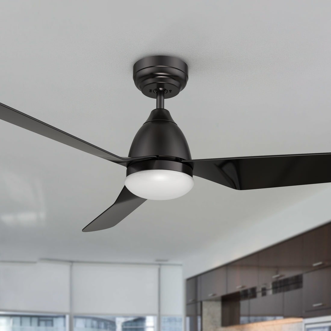 A modern Triton 52-inch ceiling fan with LED light and smart features installed in a bright, minimalist kitchen-living area. 