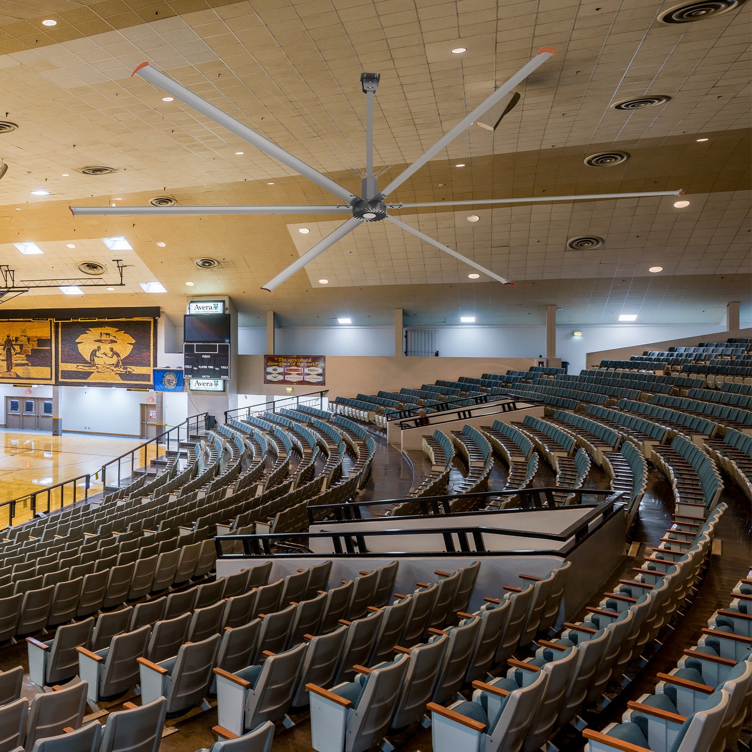 Visby 24-foot industrial ceiling fan installed in an indoor stadium, providing efficient air circulation over a large seating area. 