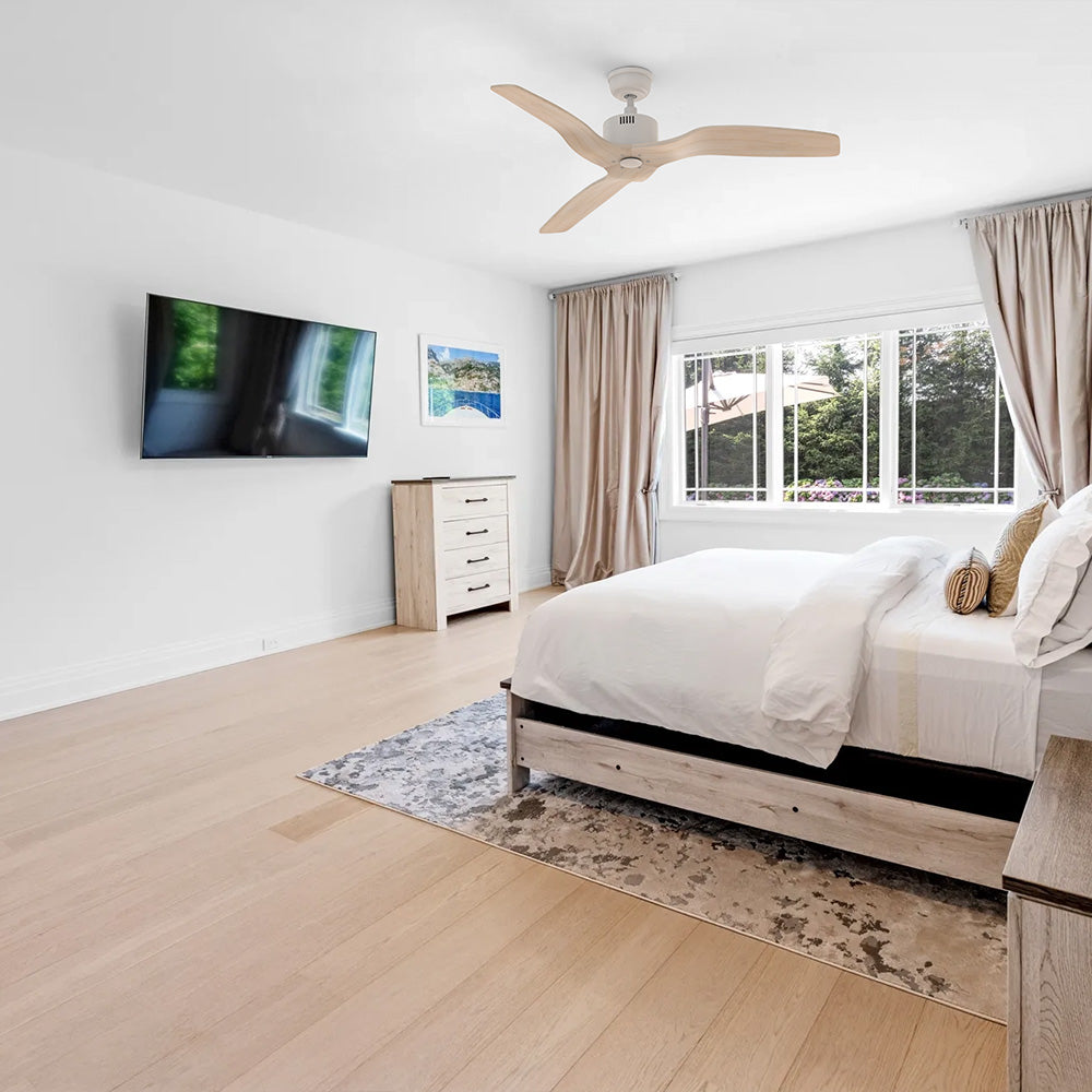 Vaulted ceiling fan installation featuring a white finish with 3 light wood grain blades inside a bright contemporary bedroom. 