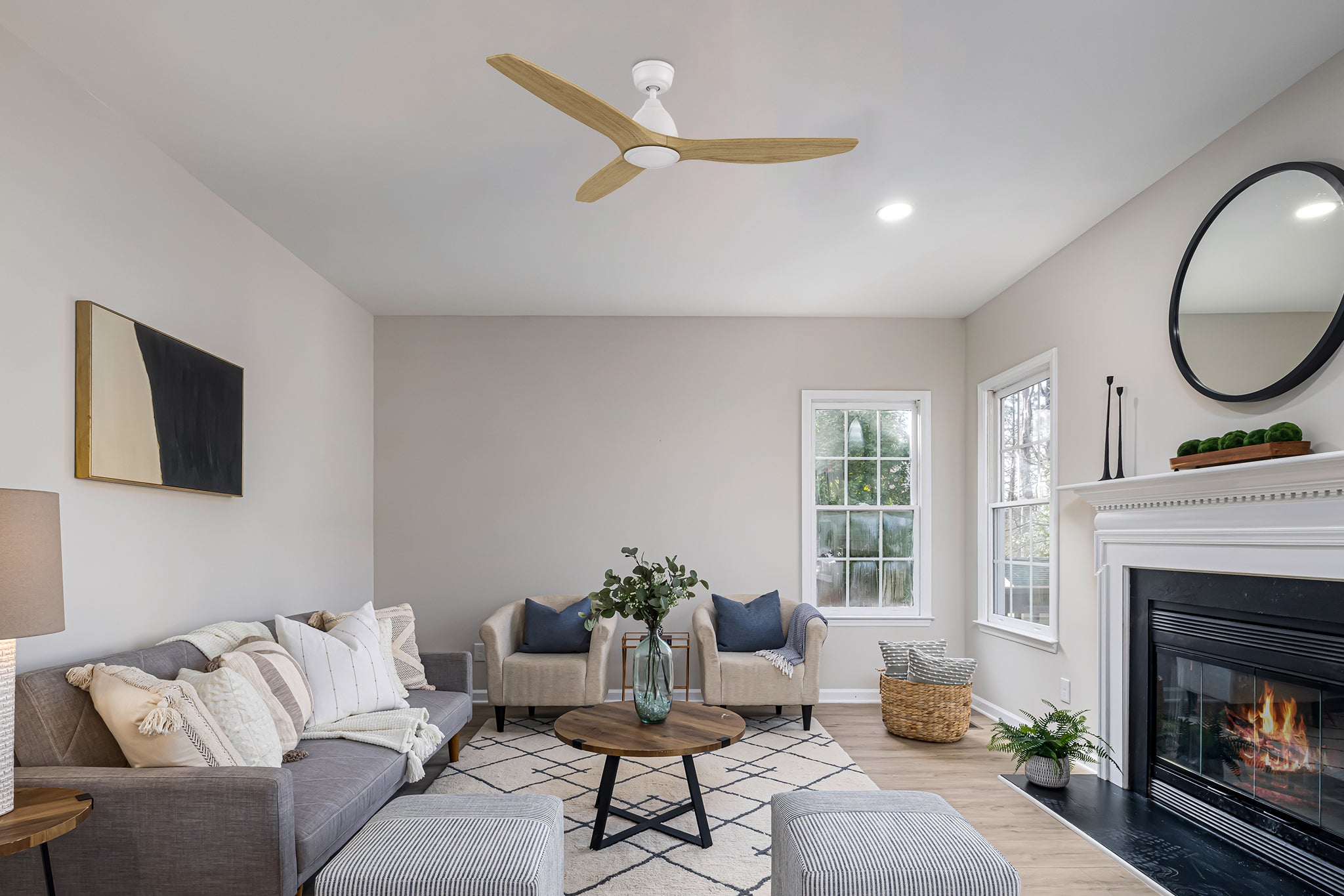 A modern living room with the Zircon ceiling fan installed. The fan features a white motor housing and three solid wood blades, seamlessly blending into a light and airy interior design.