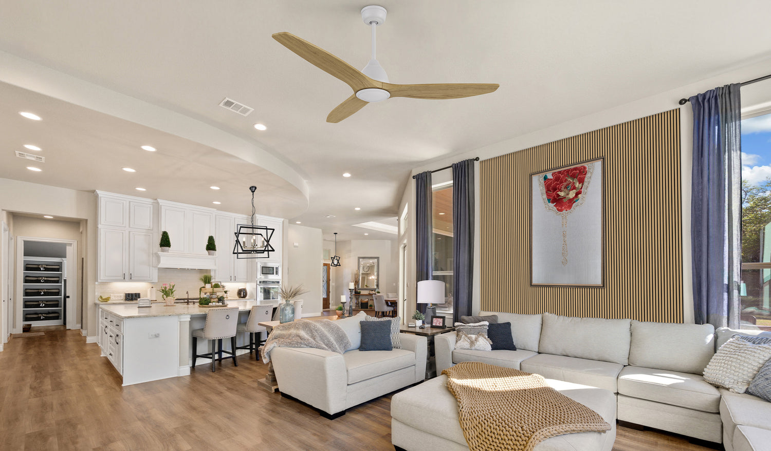 Open kitchen and living area with Lainey flush-mount ceiling fan with light, black felt acoustic oak slat wood wall panels, and vibrant artwork. Combines modern design with quiet, efficient airflow.
