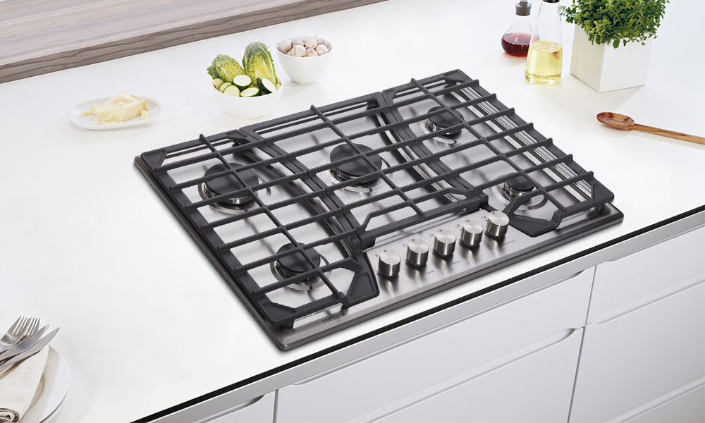 A gas cooktop with three cast-iron grates in the minimalism-style kitchen counter. 