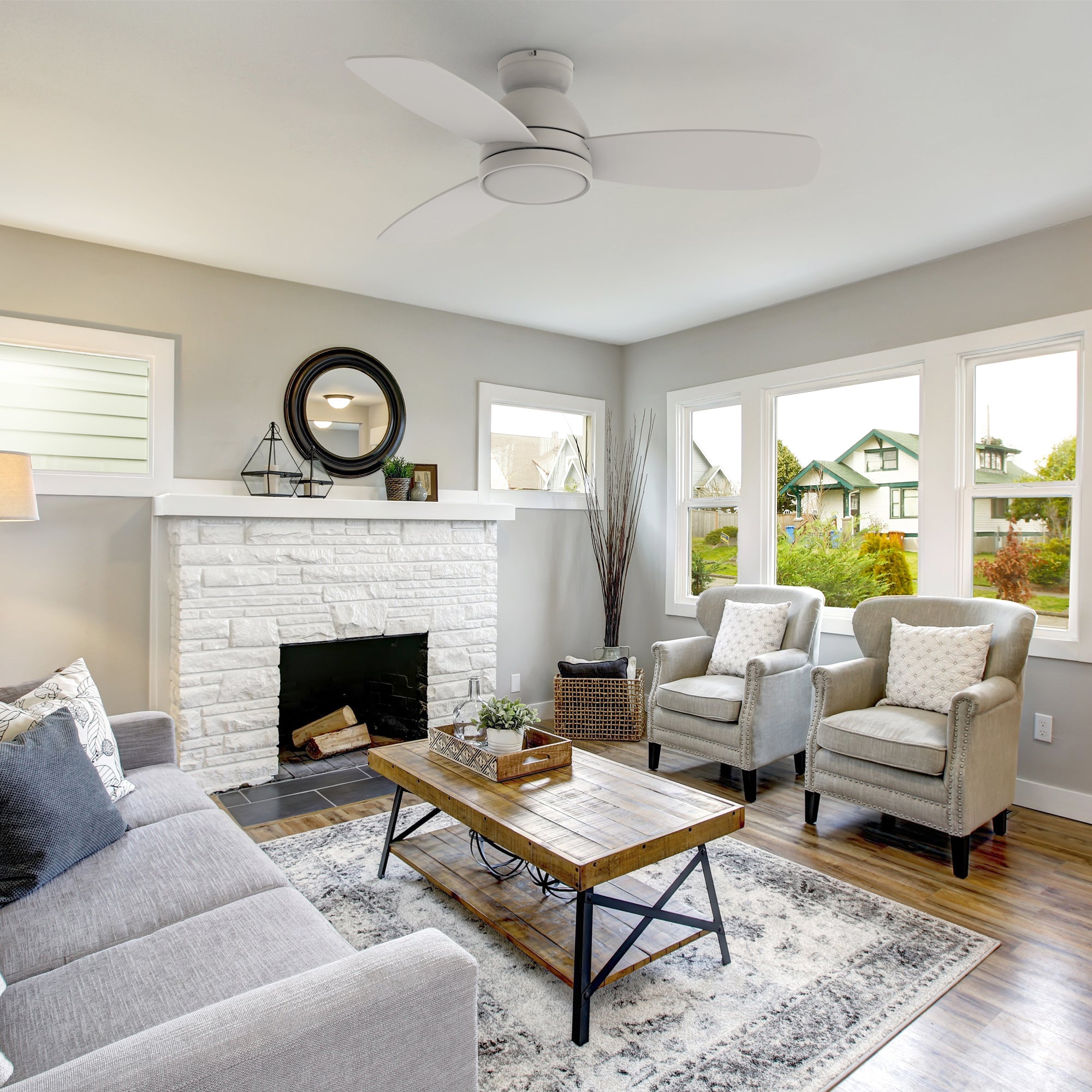 44-inch white remote ceiling fan with light for living room decoration. The white walled fireplace makes this living room more luxurious. 