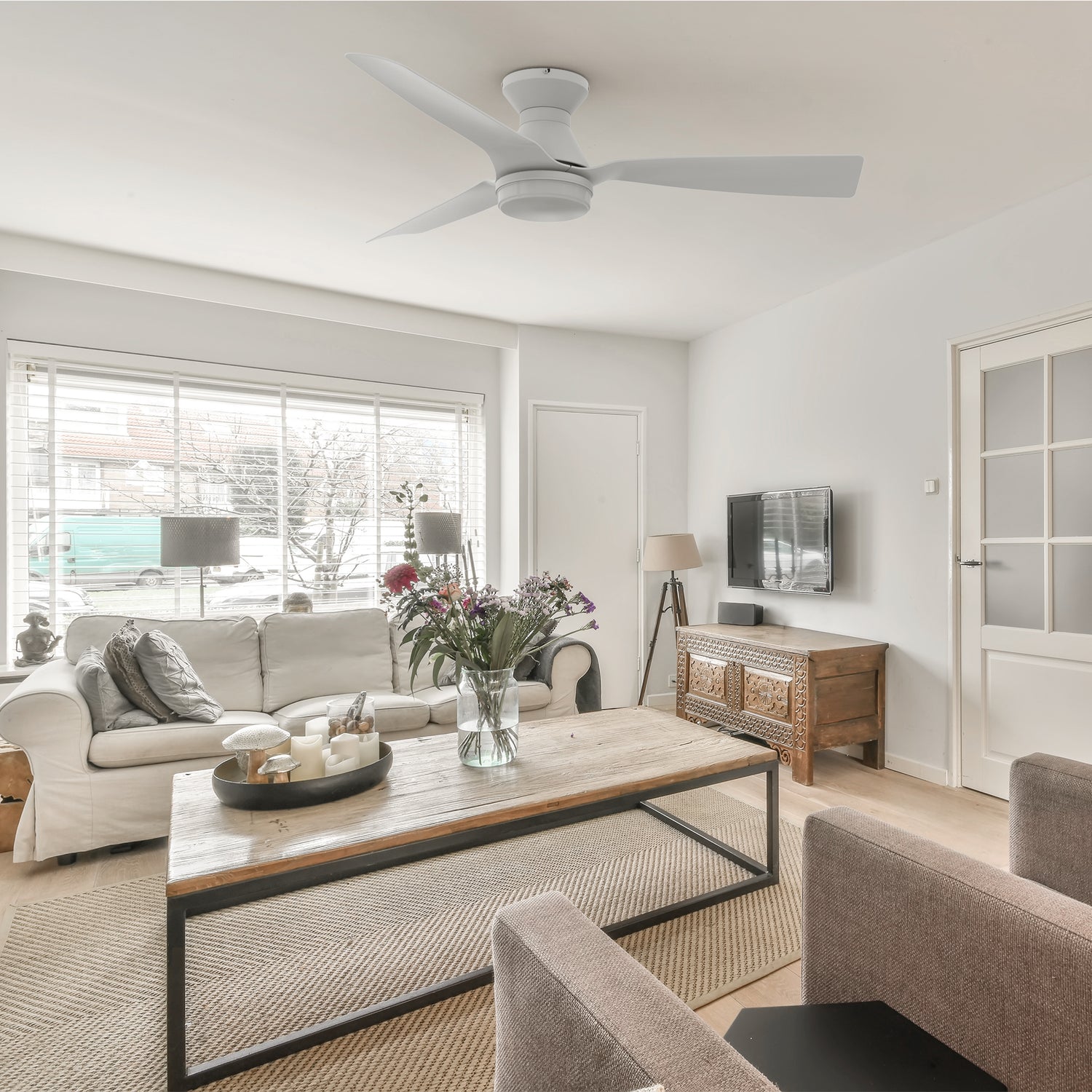 White remote ceilign fan is paired with a white three-seater sofa and interior wood grain furniture, making the living room simple and elegant. 