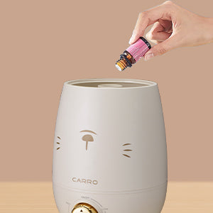 A white ultrasonic humidifier with a rabbit motif is being added with aromatherapy essential oils
