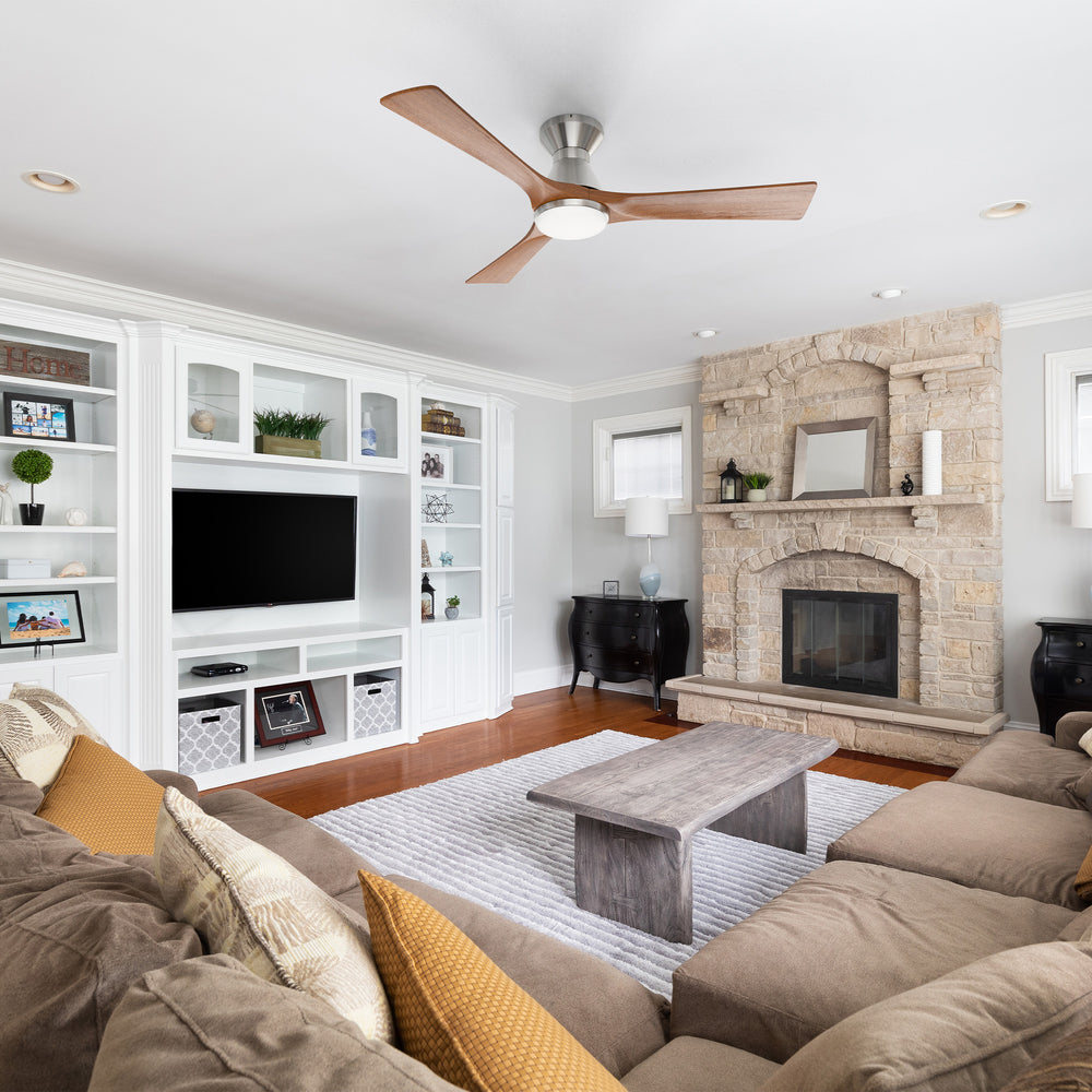 A modern living room with a brown sectional sofa, wooden coffee table, stone fireplace, built-in white shelves and TV, wood floor, gray rug, and a rustic farmhouse chic vibe. A low-profile ceiling fan with 3 blades completes the cozy Scandinavian-inspired space. 