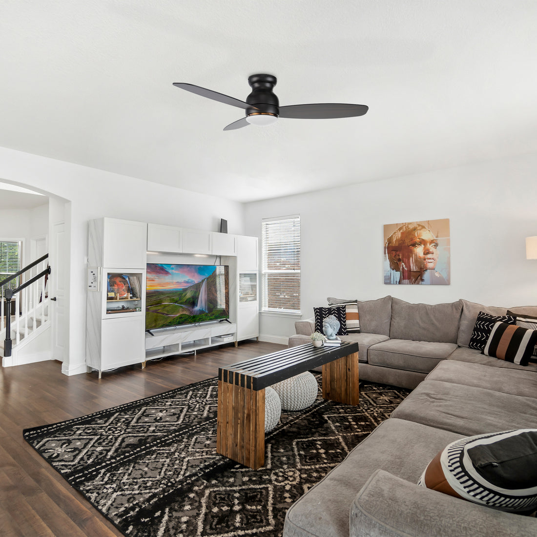Side view of a black low profile ceiling fan motor with light wood blades and integrated LED light. 