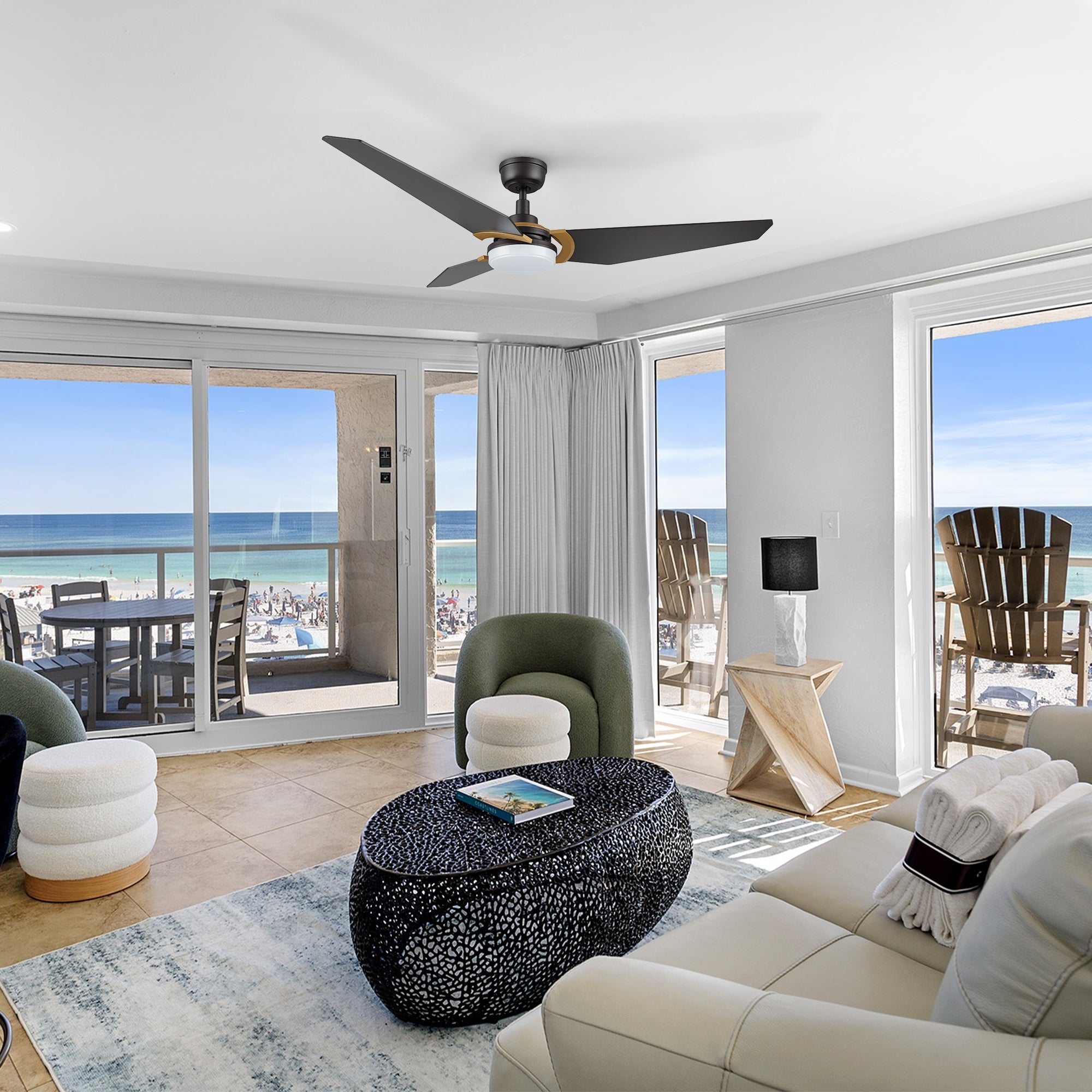 Sleek 56-inch Trailblazer smart Wi-Fi ceiling fan in matte black, installed in a modern beachfront living room. The fan complements the coastal interior with wide windows, ocean views, and contemporary furniture, blending smart comfort with minimalist design. 